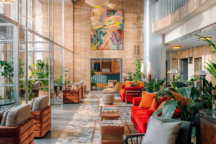 Die Hotellobby ist mit rubinroten Sofas, Sesseln im Stil der 1950er Jahre, üppigem Grün und Mid Century-Leuchtobjekten ausgestattet © JuliusHirtzberger.com